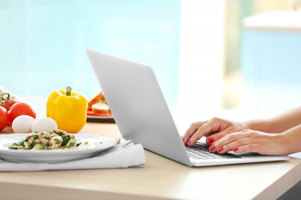 peron using a laptop near a plate of healthy food