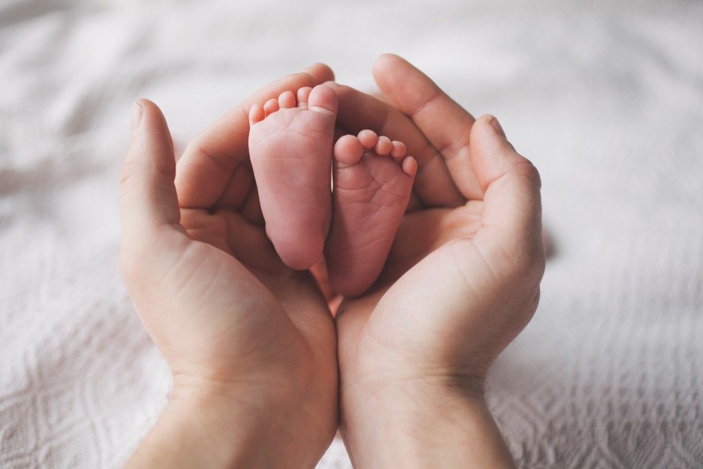 newborn baby's feet in her mother's hand