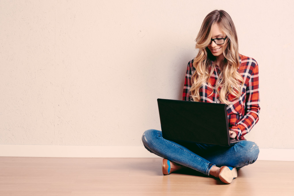 Young creative woman sitting in the floor with laptop