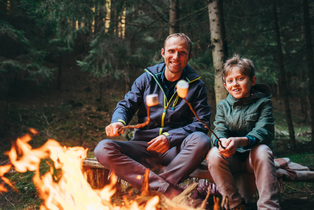 father and son cooking in campfire