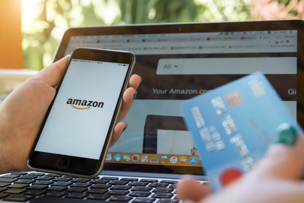 Amazon in phone and laptop with a person holding a credit card