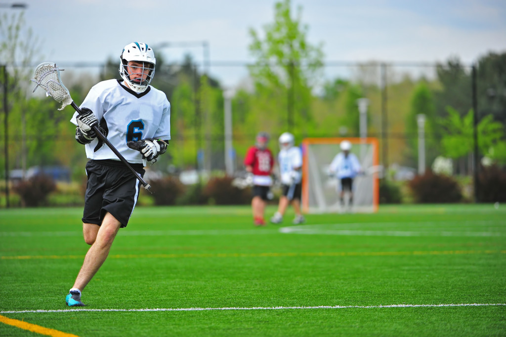A man running across the field, playing lacrosse