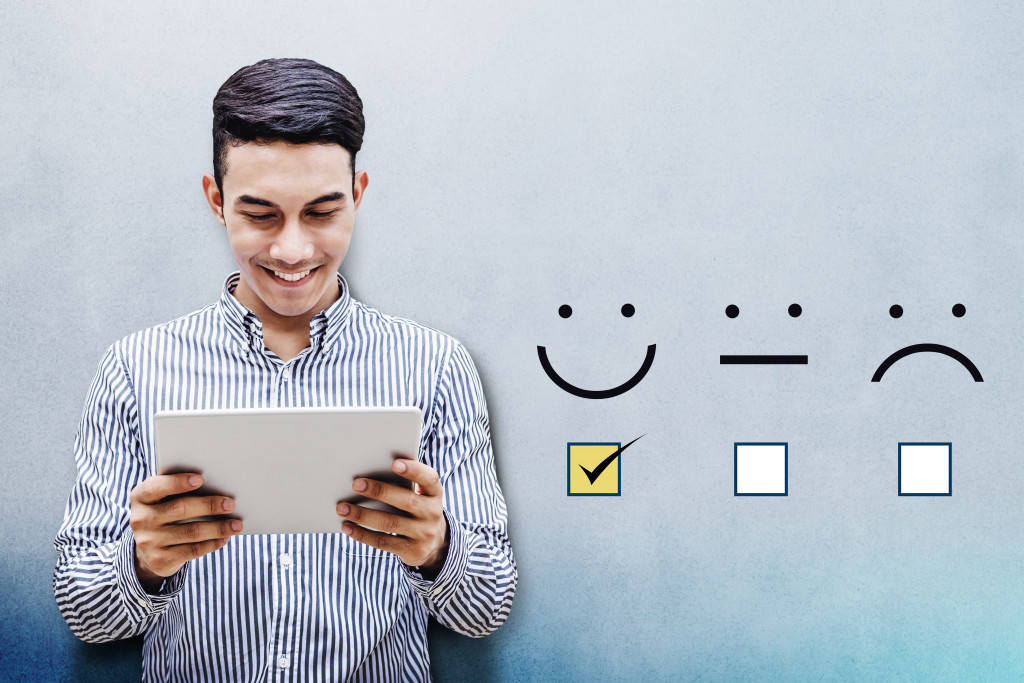 a man smiling while holding a tablet and a check mark on the smiley icon representing good customer experience