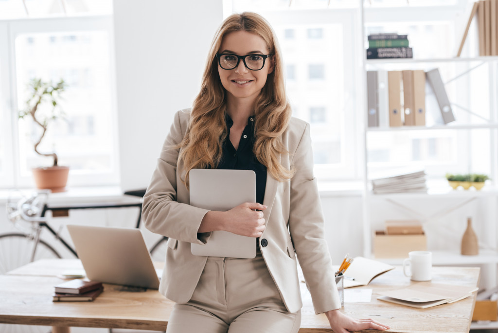 A business owner smiles confidently while standing in front of her desk